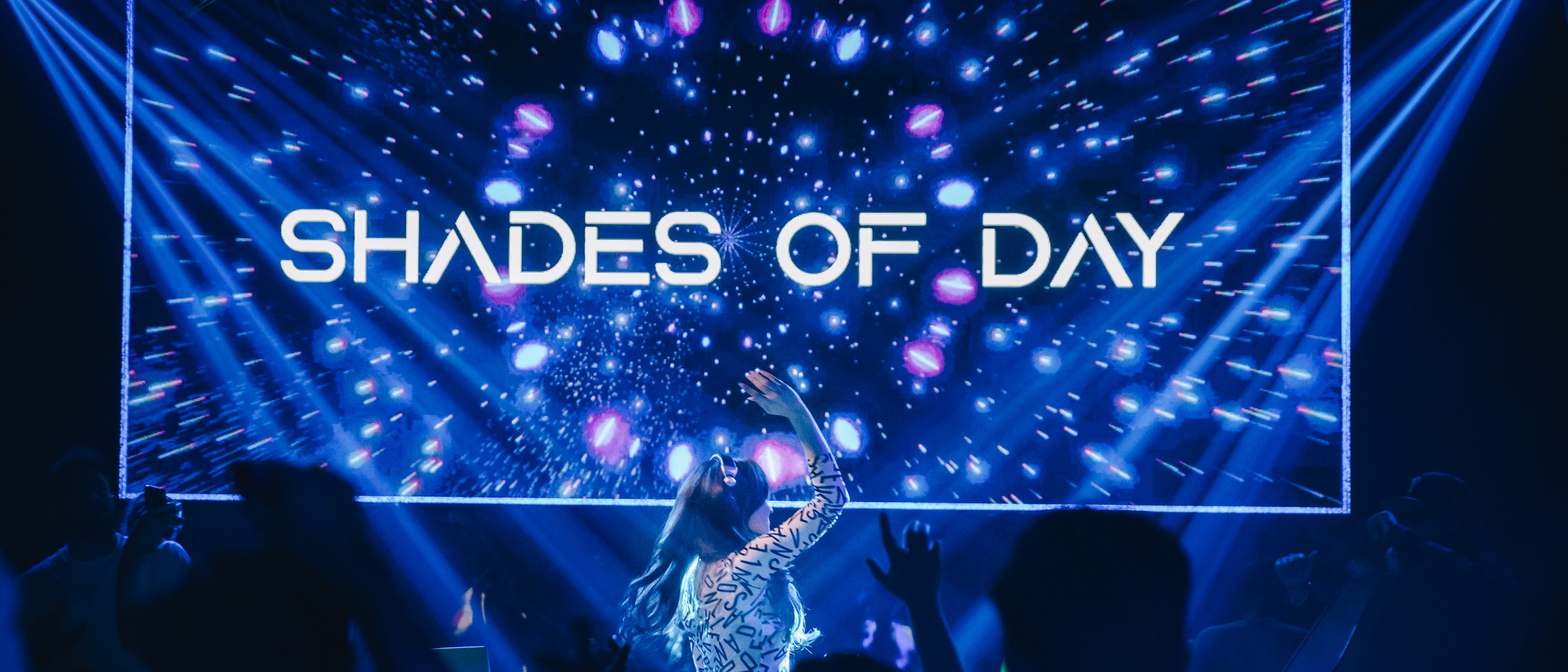 Shades of Day performing live with her arm raised to the crowd